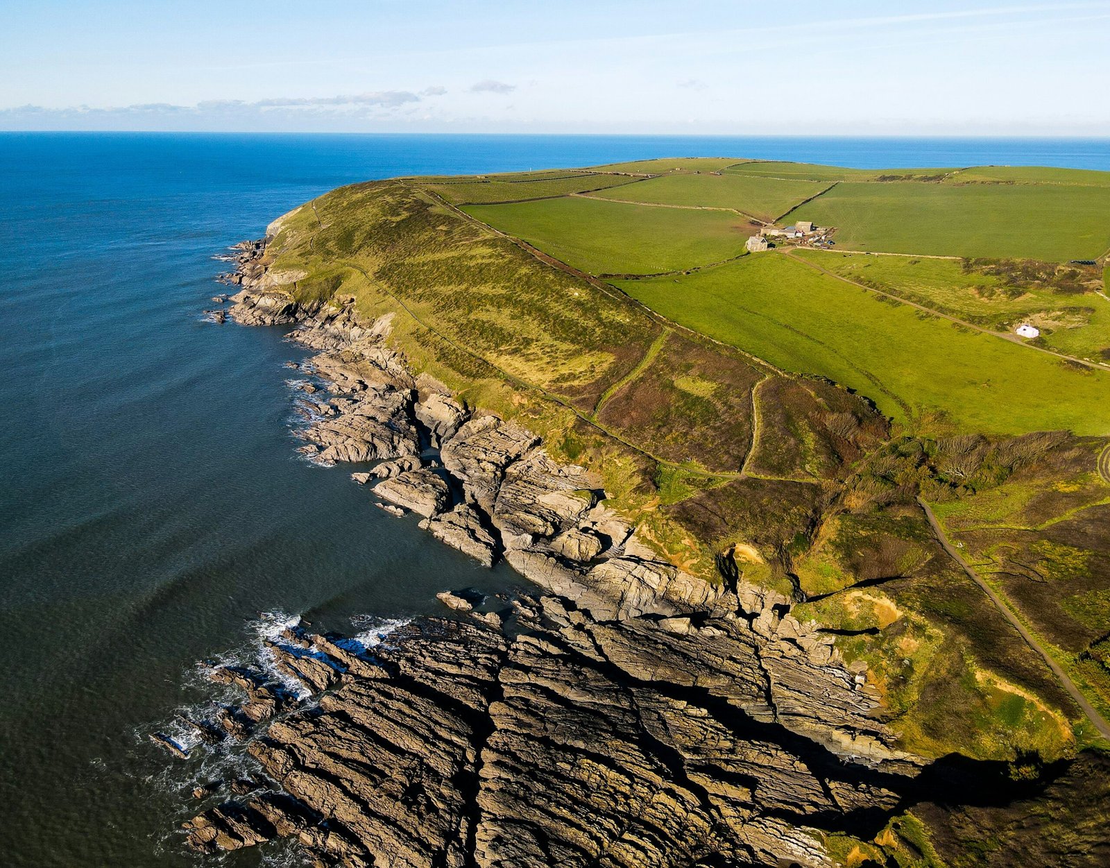 green grass covered mountain beside blue sea during daytime